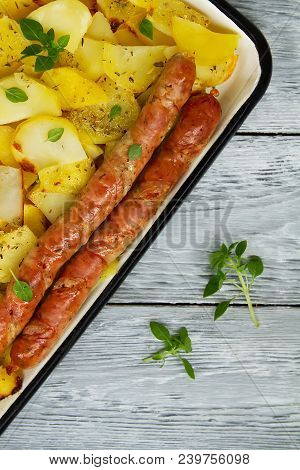 Tasy Baked Potato Slices With Fried Munich Sausages With Basil Leaves On A Baking Sheet