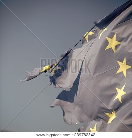 European Union Twelve Star Flag Torn And With Knots In Wind On Blue Sky Background, Close Up. Flag I