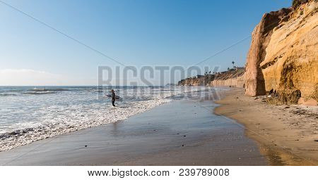 Solana Beach, California/usa - April 22, 2018:  A Lone Male Surfer Enters The Ocean Carrying A Surfb