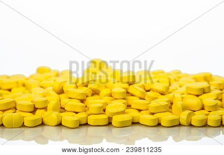 Pile Of Yellow Ovoid-rectangular Shape Tablet Pills Isolated On White Background With Copy Space. Ib