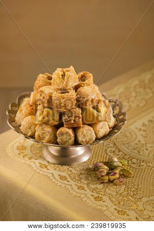 Assorted Baklava displayed on an ornamental  golden plater with few whole pistachio nuts. Authentic turkish delights.