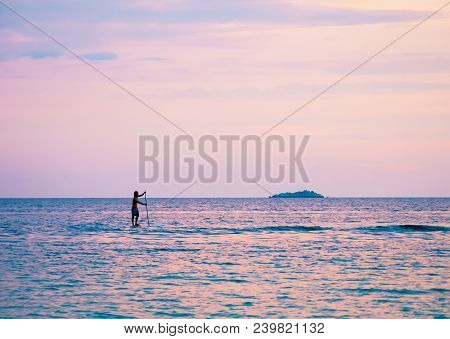 Stand-up Paddler In The Sunset On The Sea With A Small Island