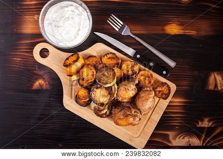 Top View Of Fried Chicken Next To Grilled Sweet Potatoes, Quash And Sour Cream Souce On Wooden Backg