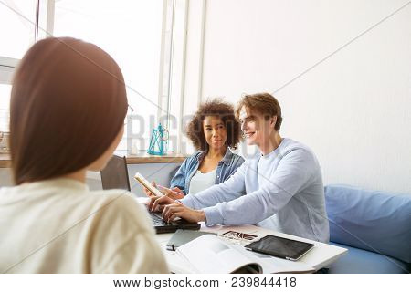 Afro American Girl And A Gy Sitting Together On The Sofa. He Is Showing Something To Her On The Lapt