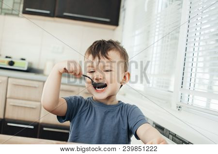 The Little Boy In The Kitchen Eagerly Eating Rice With A Spoon Independently