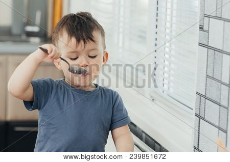 The Little Boy In The Kitchen Eagerly Eating Rice With A Spoon Independently