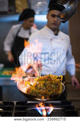 Chef cooking and doing flambe on food in restaurant kitchen