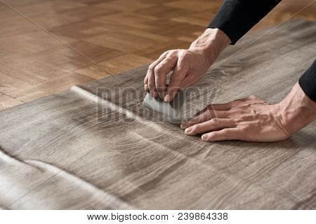 Closeup Of Carpenters Hands Removing Air From Self-adhesive Film
