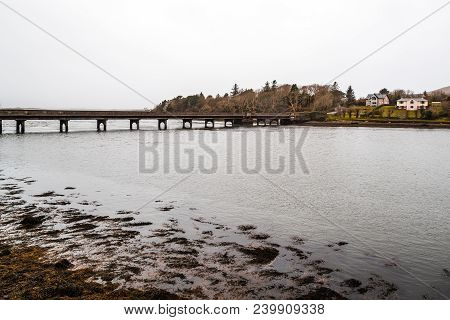 Scenic View Of Bridge Over Water In Lowlands In The Wild Atlantic Way Of Ireland Against Cloudy Sky