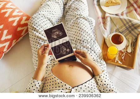 Pregnant Woman Wearing Pijama With Book, Tea, Cake Relaxing At Home. Top View