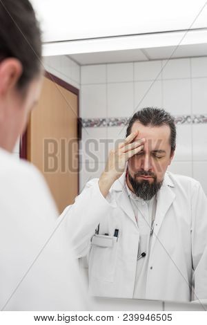 Doctor In Front Of A Mirror Have Headache And Looks Stressed Near To An Burnout