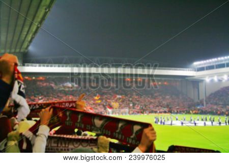 Blurred Background Of Football Players Playing And Soccer Fans In Match Day On Beautiful Green Field