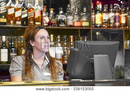 Portrait Of Woman Bartender Registrating New Order By Cash Register. A Restaurant Worker Registratin