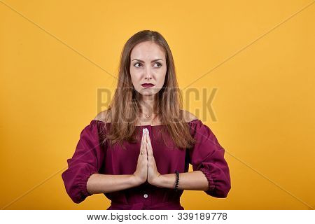 Young Girl In Praying Position. Woman Holds Hands Together And Looks With Please For Forgiveness. Be