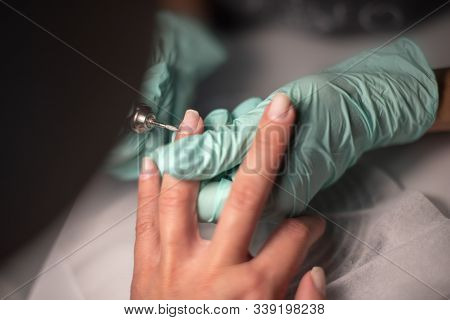 A Manicure Hand With A Nail Lies On A Manicure Hand In Blue Hygienic Gloves.hands On The Manicure Of