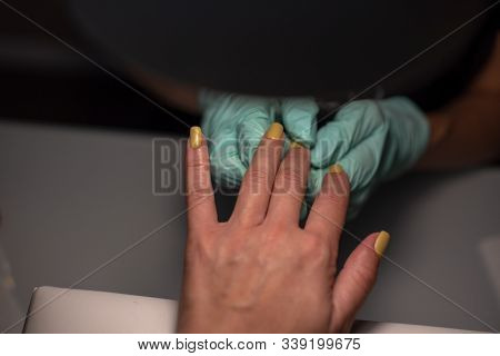 A Manicure Hand With A Nail Lies On A Manicure Hand In Blue Hygienic Gloves.hands On The Manicure Of