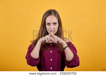 Young Girl In Burgundy Bluse With Bow Showing A Sign Of Silence Over Isolated Orange Background With