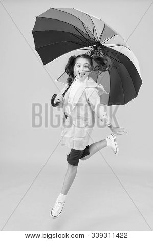 I Do Not Care. Carefree Schoolgirl Jumping With Umbrella Waterproof Rain Coat. Autumn Rain. Rainy Da