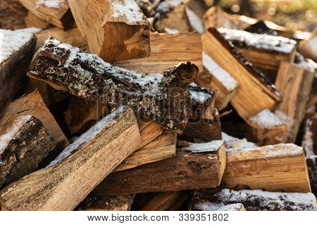Firewood Stacked In Winter. Wood Pile With Snow Stacked For Firewood. Chopped Stock Of Firewood Unde