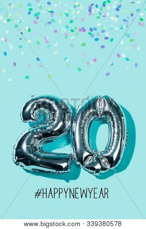 some confetti, two silvery number-shaped balloons forming the number 20, as the new year, and the hashtag happynewyear against a blue background