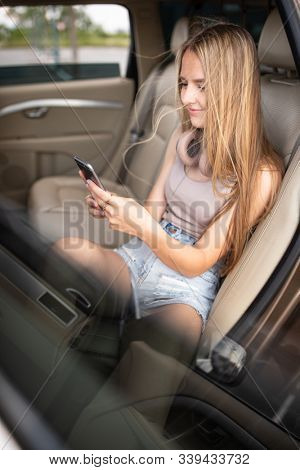 Cute teenage girl listening to her favorite music/audiobook on hig-end headphones during a roadtrip