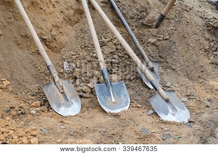 Dirty Used Shovels Are Thrown To The Ground During The Lunch Break. A Group Of Dirty Shovels On The 