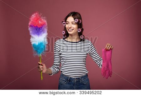 A Girl In Curlers And Gloves For Cleaning Holds Pipidaster In Her Hands.