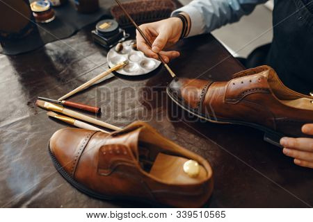 Bootmaker with brush tints shoes, footwear repair
