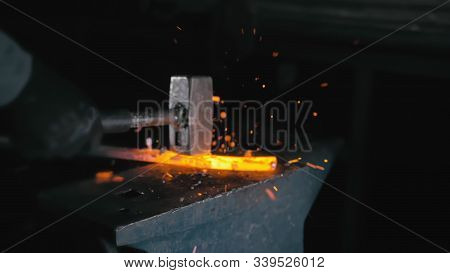 Forge Workshop. Smithy Manual Production. Hands Of Smith With Hammer Hit On Glowing Hot Metal, On Th