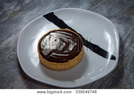 Tartelette Au Chocolat, A Typical French Pastry Chocolate Tart Pie, On Display On A White Plate On A