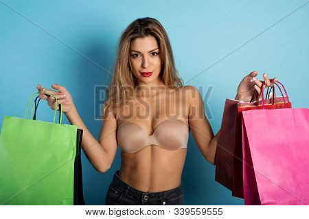 Blonde Girl Has A Lot Of Shopping Bags. Concept Of Shopaholic And Shopping. Cyan Background