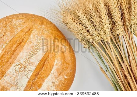 Round Homemade Bread With Wheat Ears. Freshly Baked Round Whole Wheat Bread And Sheaf Of Wheat Ears.