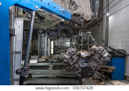 Used V8 Engine With Eight Cylinders Suspended Mounted On A Crane For Overhaul Repair And Installatio