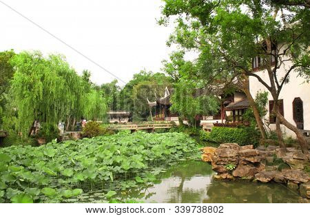 Pavilion, pond with lotuses and bridge in Humble Administrator's Garden in Suzhou, China. Summer day