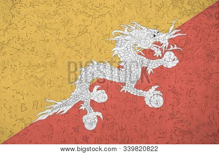 Bhutan Flag Depicted In Bright Paint Colors On Old Relief Plastering Wall. Textured Banner On Rough 