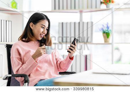 Happy Asian Woman Using Smart Phone And Smilling At Table Office In Home. Asian Female Holding Cellp