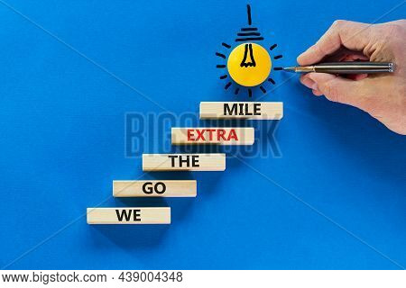 We Go The Extra Mile Symbol. Wooden Blocks With Words We Go The Extra Mile. Light Bulb Icon. Busines
