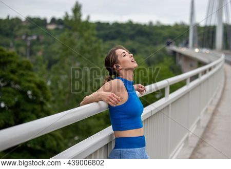 Female Athlete Relaxing Leaning On Brigde After Jogging. Young Runner Breathing Resting Outdoors.
