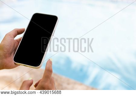 Female Hand Holding Smartphone Near Swimming Pool. Closeup, Mock Up.