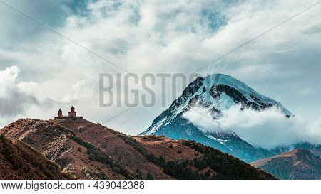 Beautiful View On Holy Trinity Church Or Gergeti Trinity Church Over Kazbek Mountain. View From Step