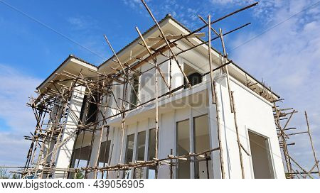 Construction Of Houses And Wooden Scaffolding. White Modern Single House Under Construction In Botto