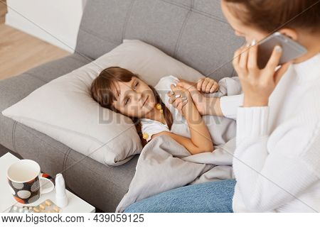 Closeup Portrait Of Mother Calling A Doctor Because Of Her Little Daughters Illness, Calls An Ambula