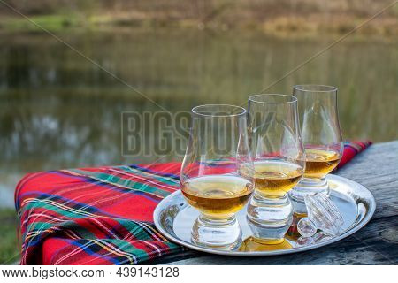 Tasting Glasses Of Scotch Whisky Strong Drink And Red Scottisch Tartan On Old Outdoor Table With For