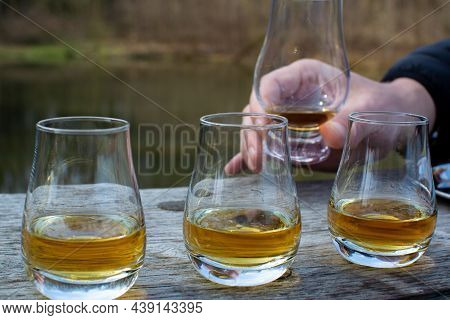 Tasting Glasses Of Scotch Whisky Strong Drink On Old Outdoor Table With Forest Lake On Background