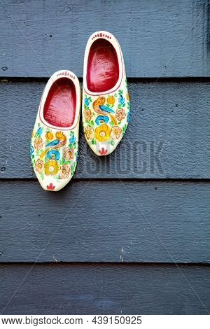 A pair of klomps against the background of a wooden wall. Old wooden Dutch shoes - klomps. Traditions of Holland. Background