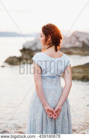 Kotor, Montenegro - 21.06.17: Woman In A Blue Dress Stands Holding Her Hands Behind Her Back On The 