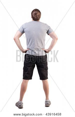 背面図ハンサムな男の t シャツとショート パンツを見上げてします。若い観光客に立って。背面ビュー人