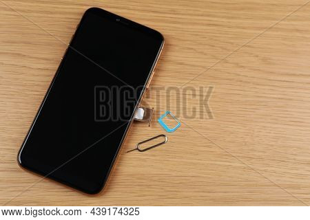 Mobile Phone With Sim Card In Tray And Ejector Tool On Wooden Table, Flat Lay. Space For Text