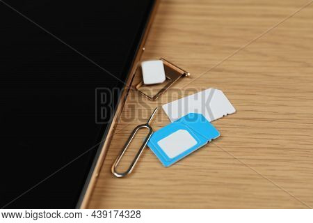 Sim Cards, Mobile Phone And Ejector Tool On Wooden Table, Closeup