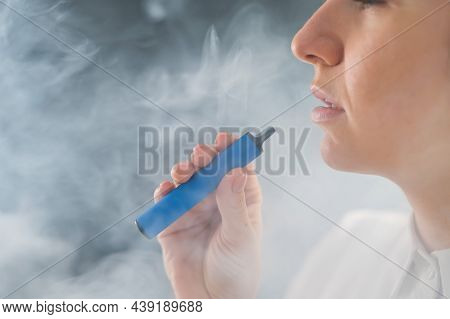 Caucasian Woman Smokes A Disposable Vape In The Studio.